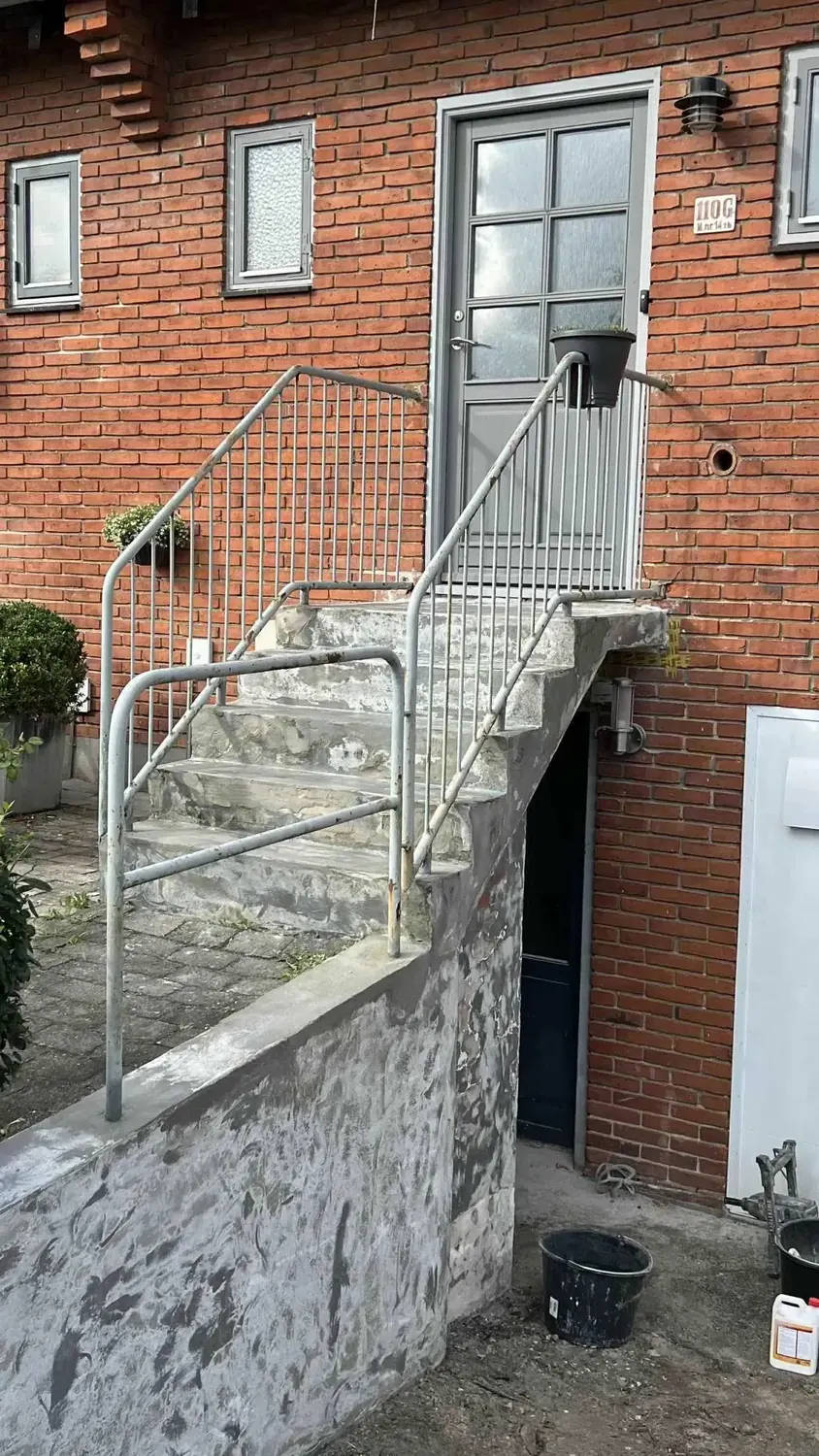 Nedslidte betontrin med alger og løs, ujævn overflade før istandsættelse